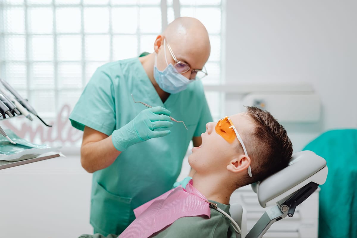 A dentist talking with a teenage patient in the treatment chair