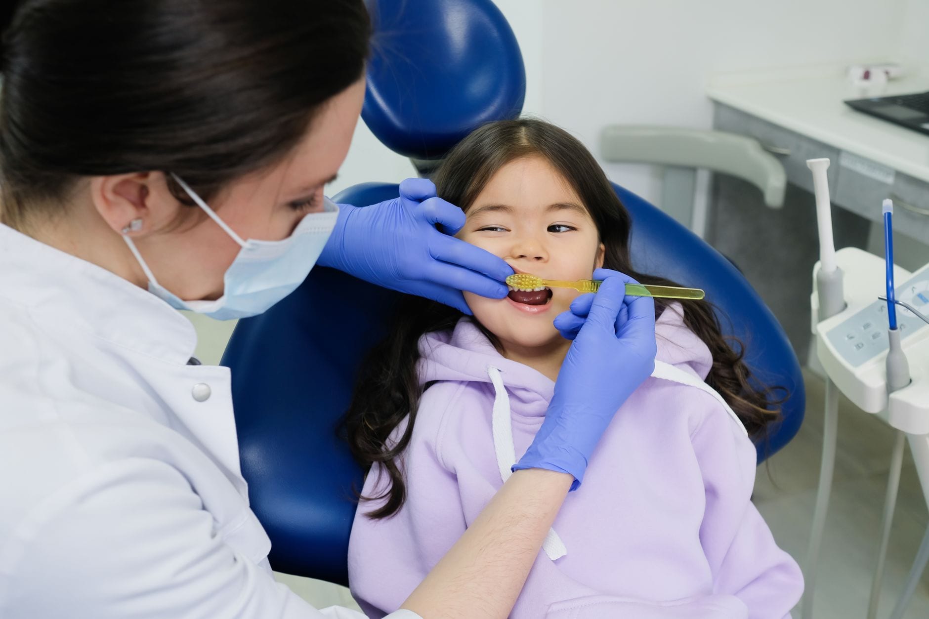A hygienist gently showing a nervous young patient how a cleaning works