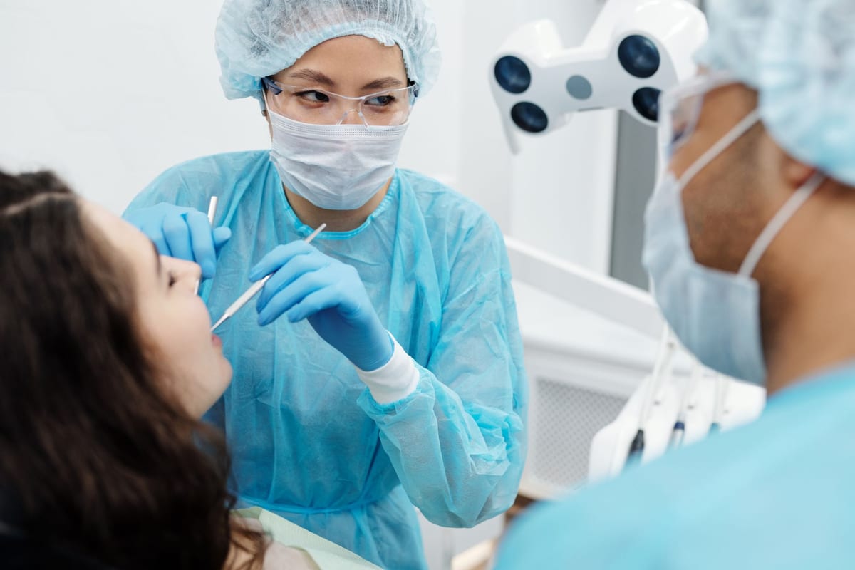 A dentist matching a tooth shade against a shade guide during a cosmetic consultation