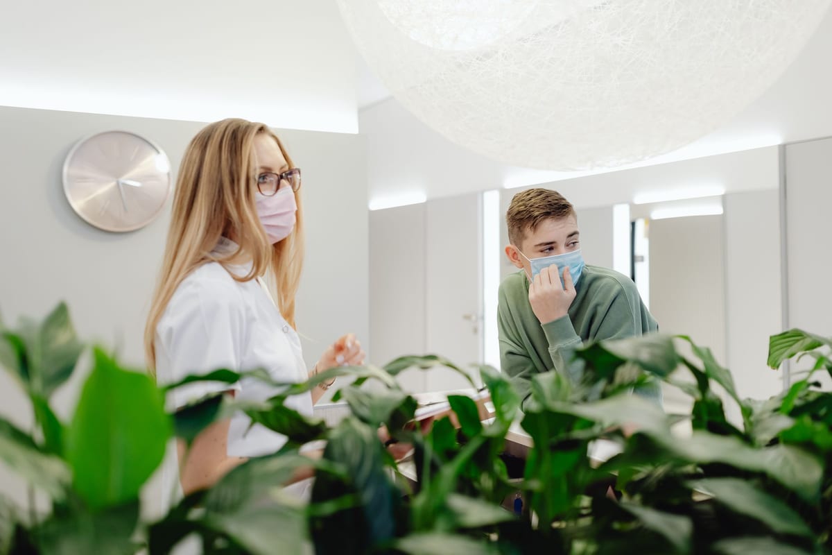 A clinician greeting a patient in a bright, plant-filled clinic reception